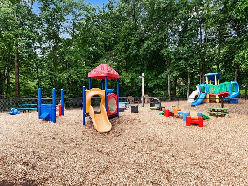 Colorful playground with multiple slides, swings, and other play structures on wood chips