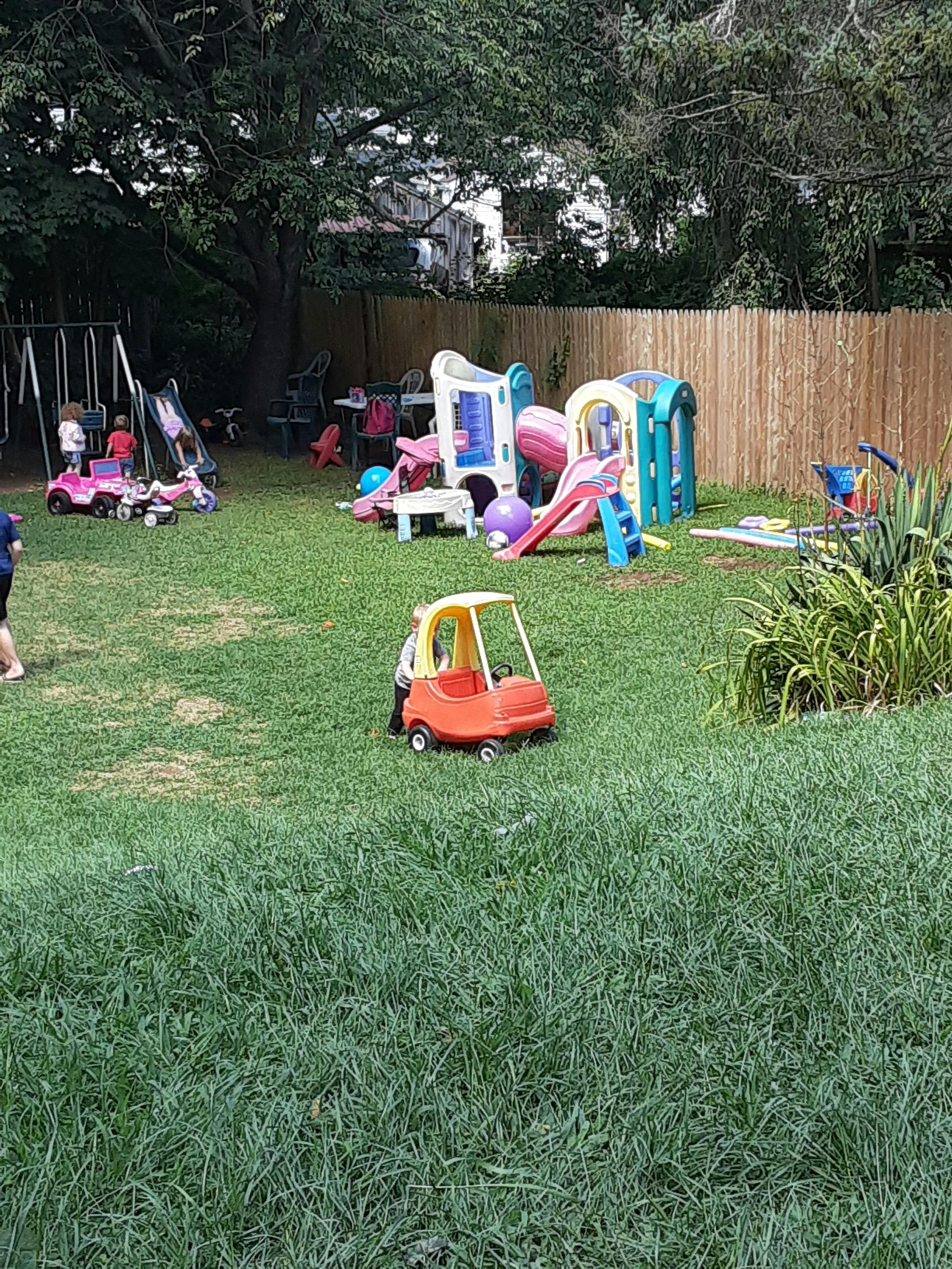 Children playing on a swing set and playground equipment in a grassy yard