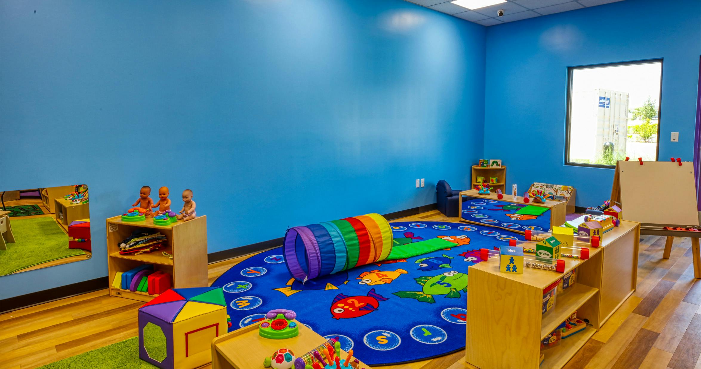 Child's playroom with blue walls, a fish-patterned rug, and play tunnel