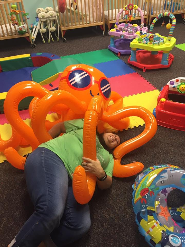 Person lying on floor with large inflatable orange octopus