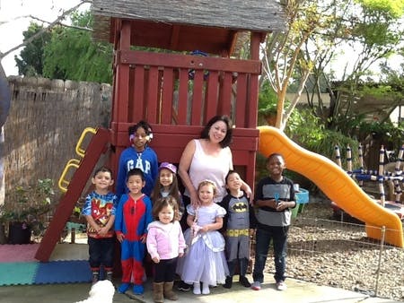 Adult and multiple children posing in front of a playground structure