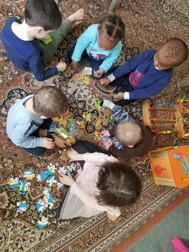 Multiple children playing with toys on a rug