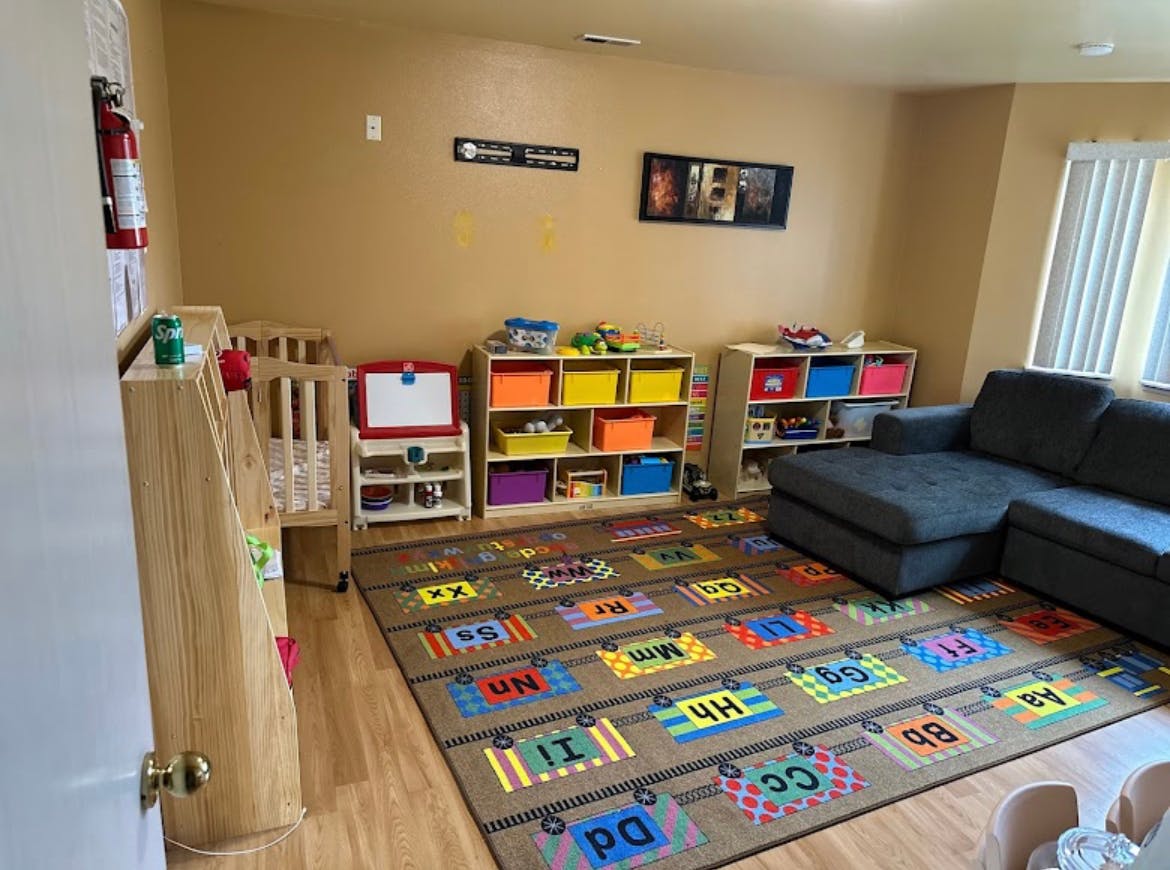Playroom with a colorful alphabet rug, shelves with toys, and a sectional sofa