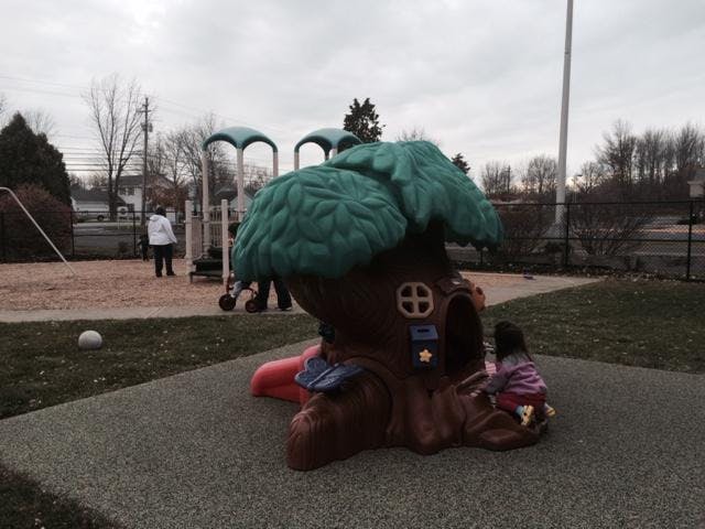 Child playing in a treehouse-shaped toy on a playground