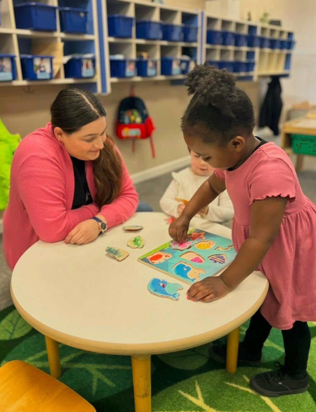 A person and children working on a puzzle at a round table
