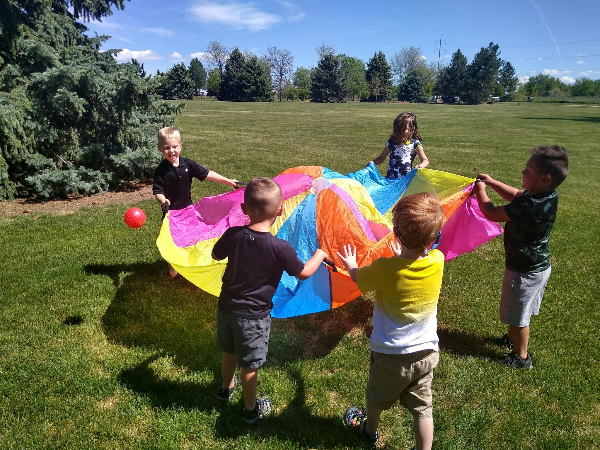 Children playing with a colorful parachute outdoors