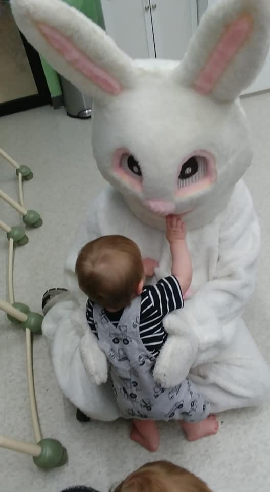 Child reaching out to touch a person in a white bunny costume