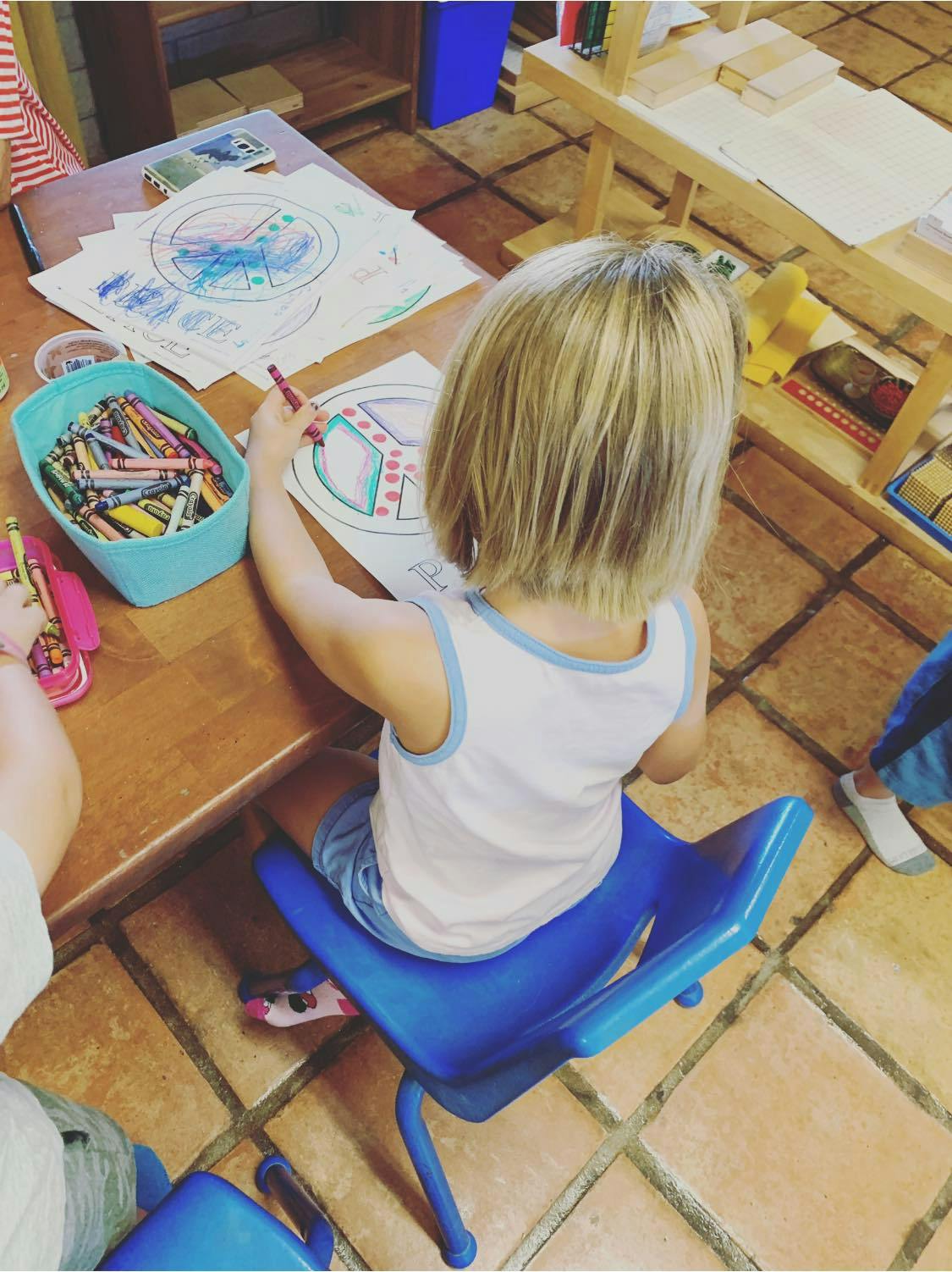 Child coloring a peace sign drawing at a table