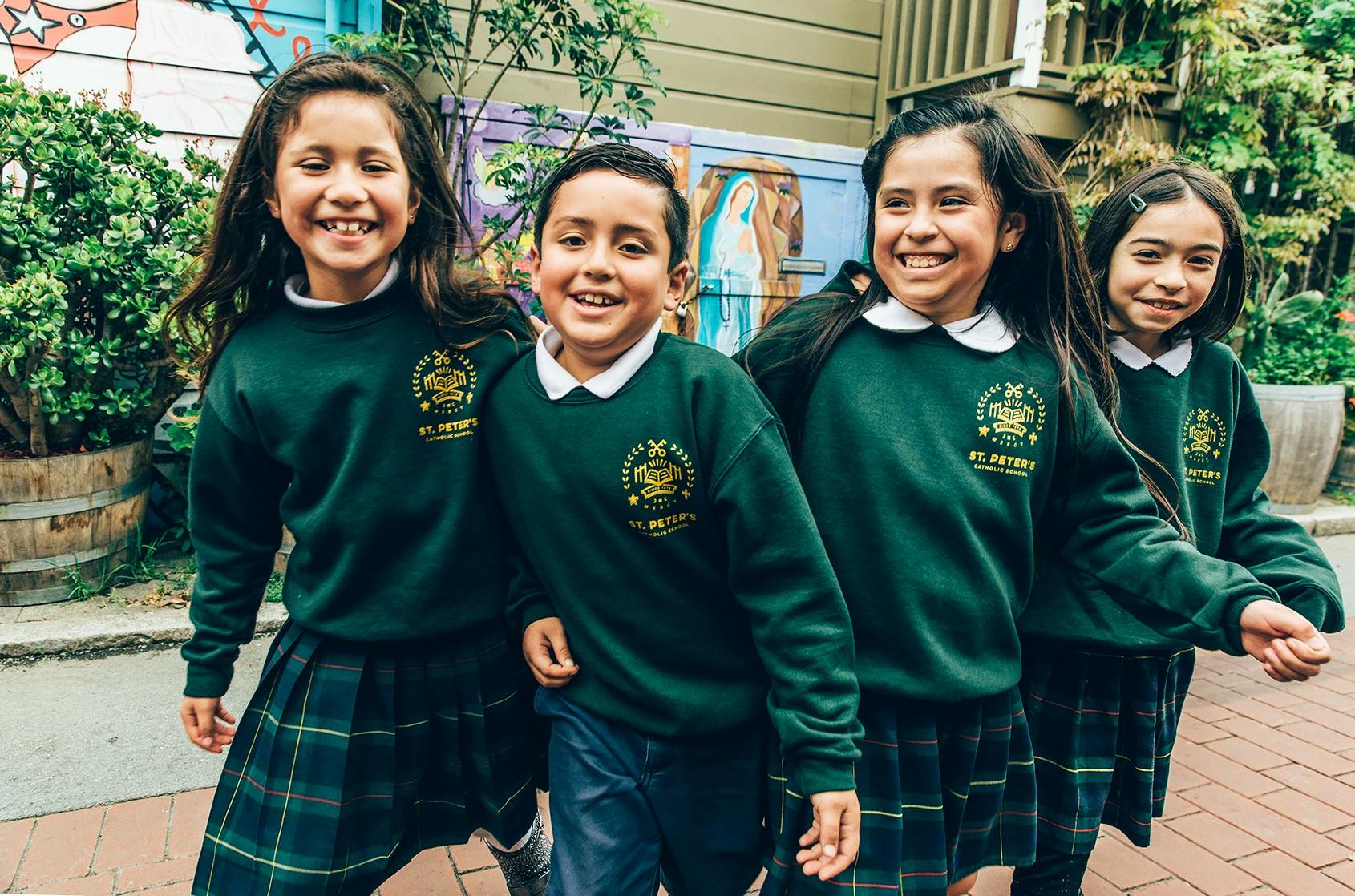 Four children in green school uniforms and plaid skirts
