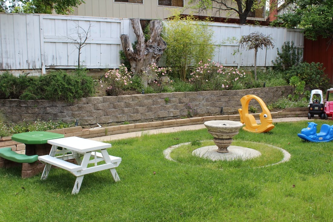 Backyard with a small picnic table, fountain, and children's toys