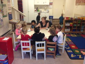 Adult and children sitting at a table in a classroom
