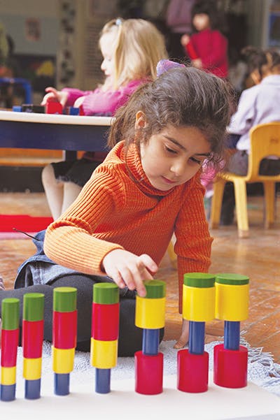 Child playing with colorful stacking blocks in a classroom