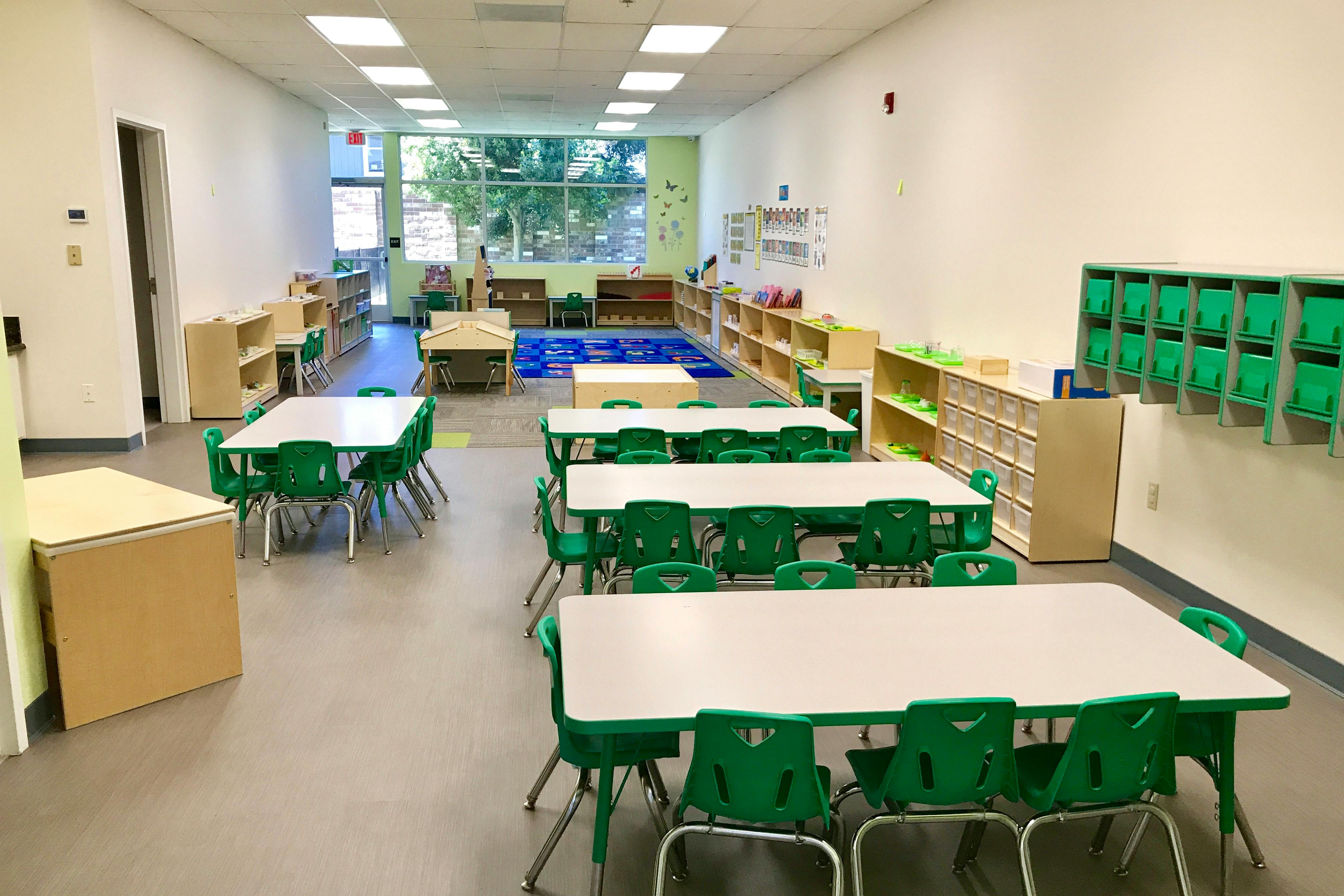 Empty classroom with small tables and green chairs