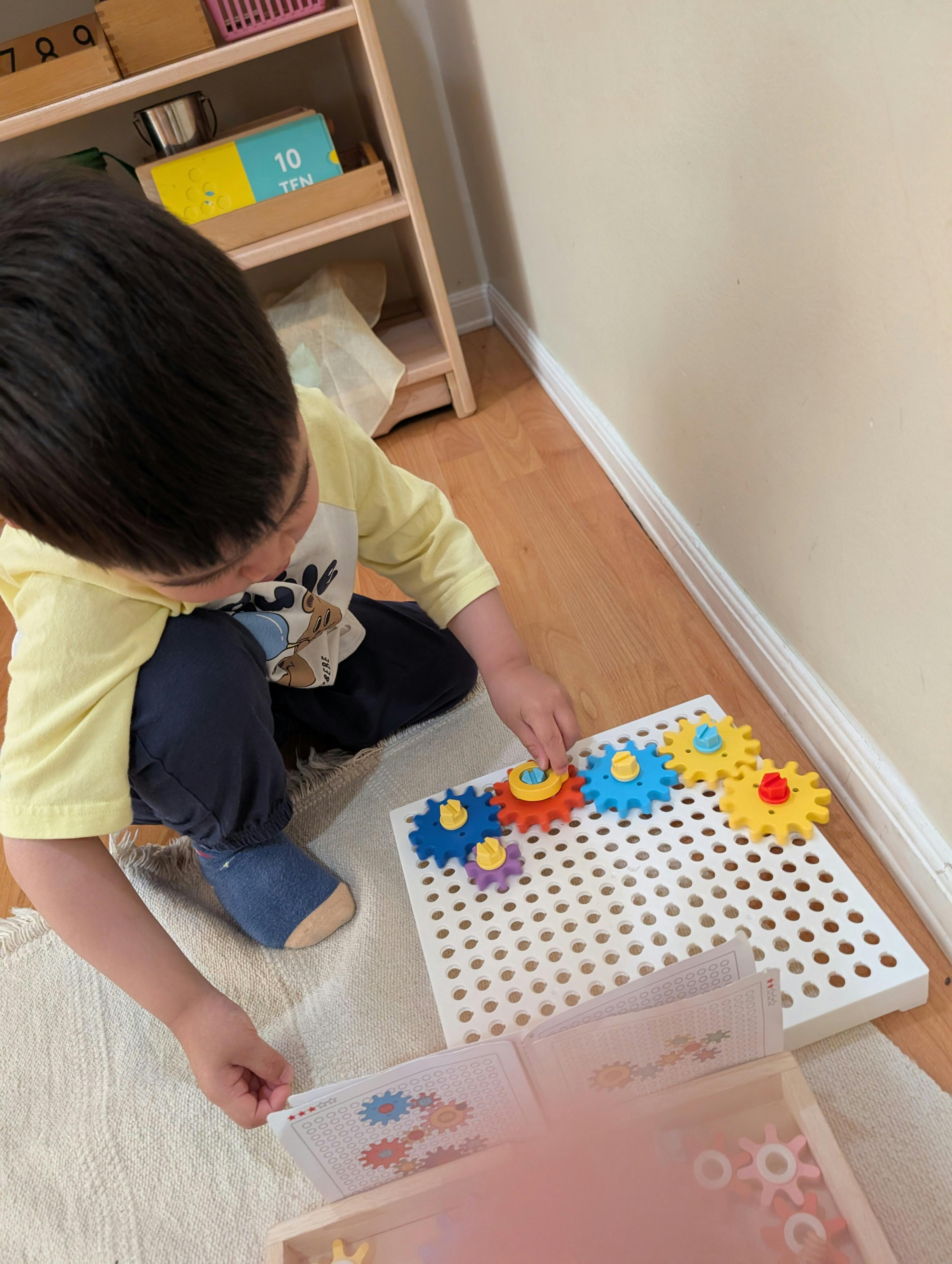 Child playing with colorful gears on a white pegboard