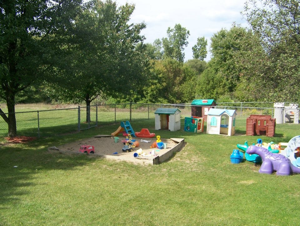 Outdoor playground with sandbox, slide, playhouses, and toys