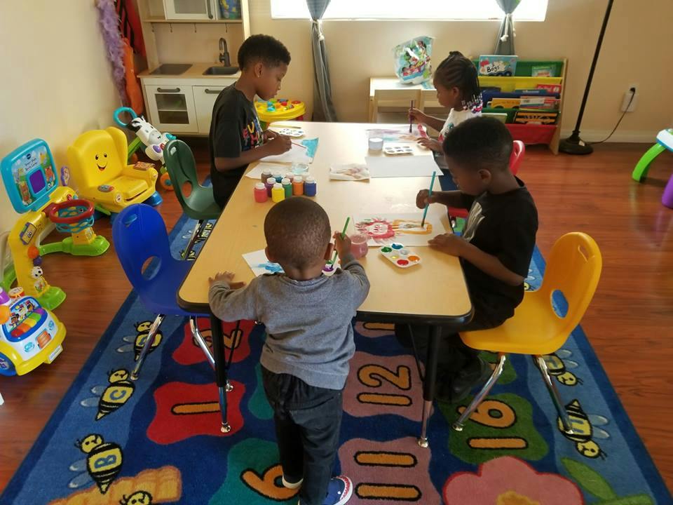Children painting at a table in a classroom