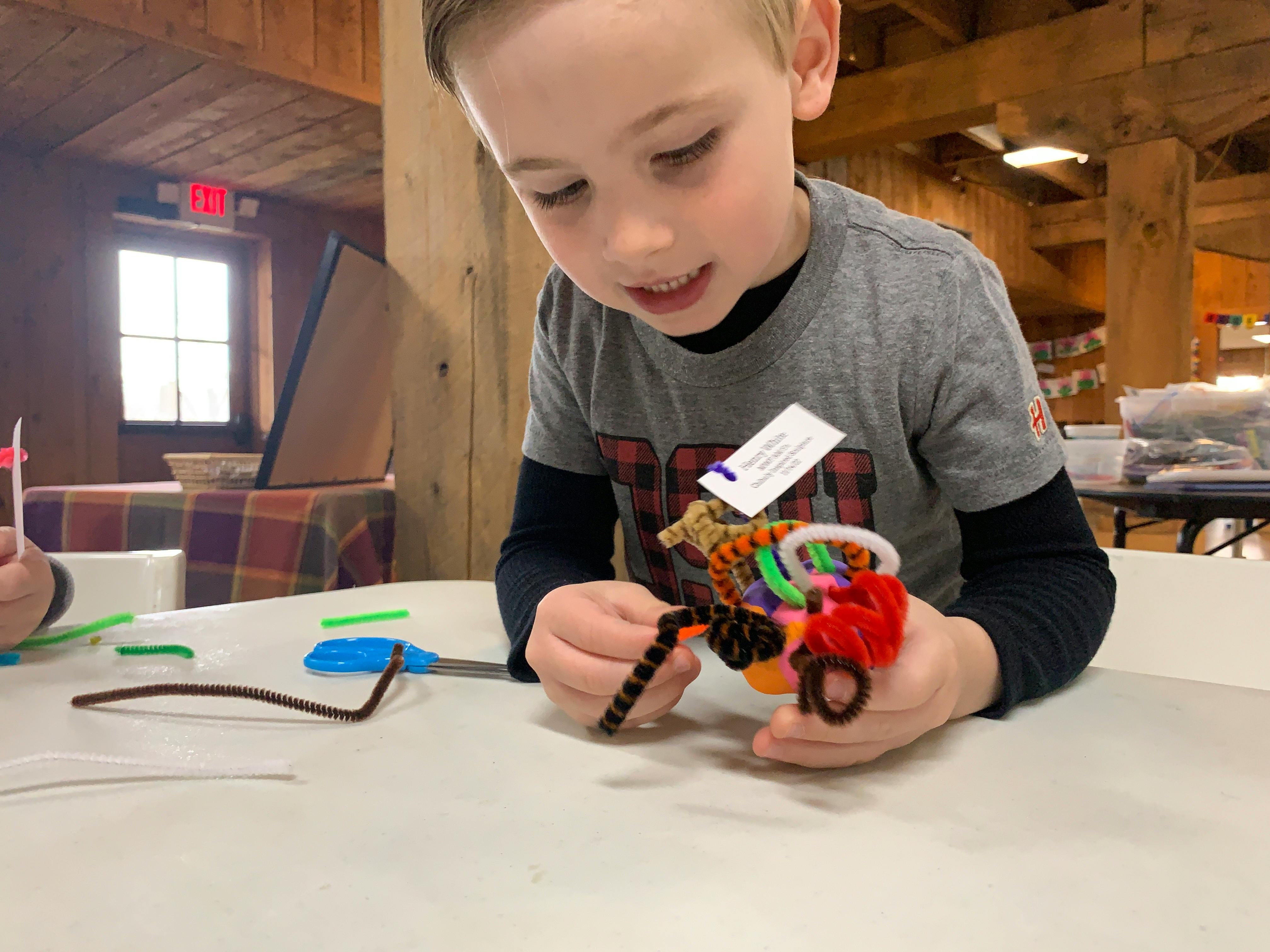 Child holding a colorful craft made from pipe cleaners