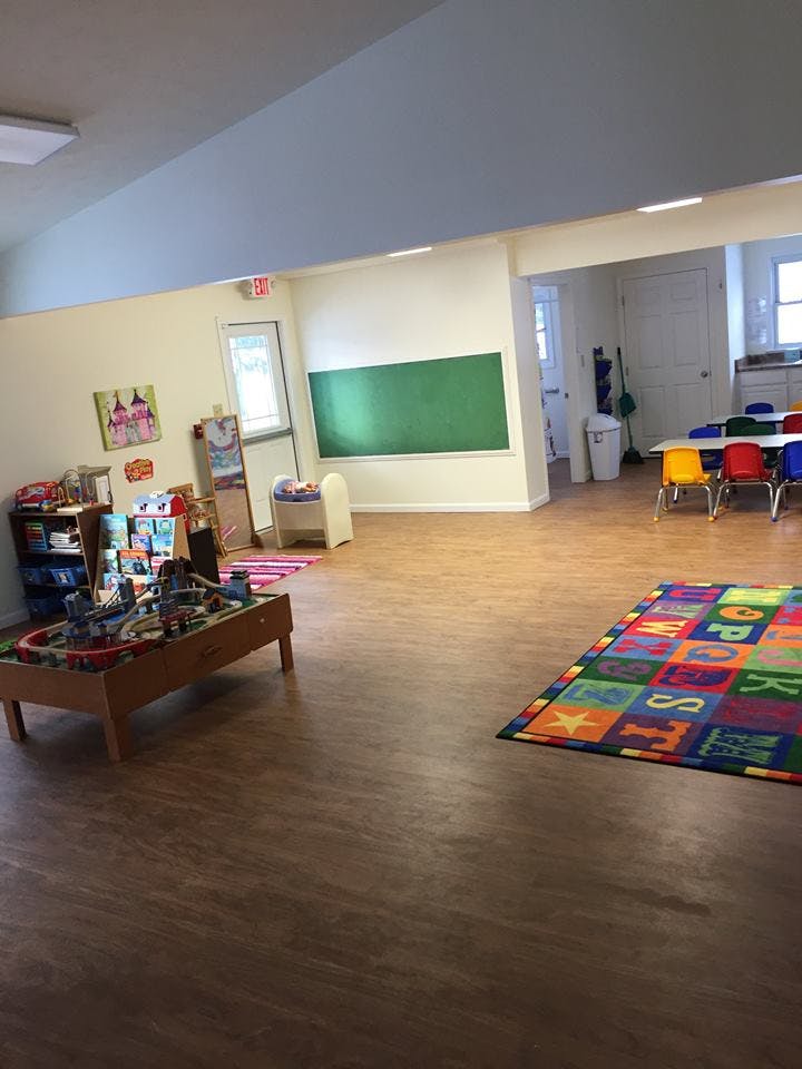 Classroom with a train table, colorful alphabet rug, and small chairs
