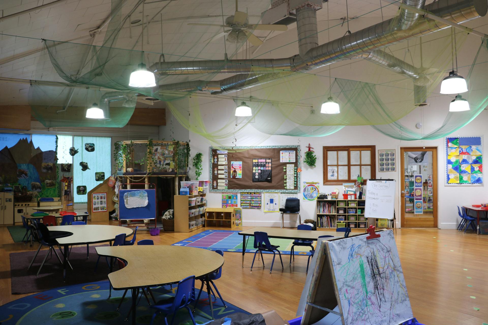 Empty classroom with tables, chairs, and colorful rugs
