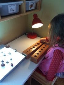 Child working at a desk with a light table and wooden blocks