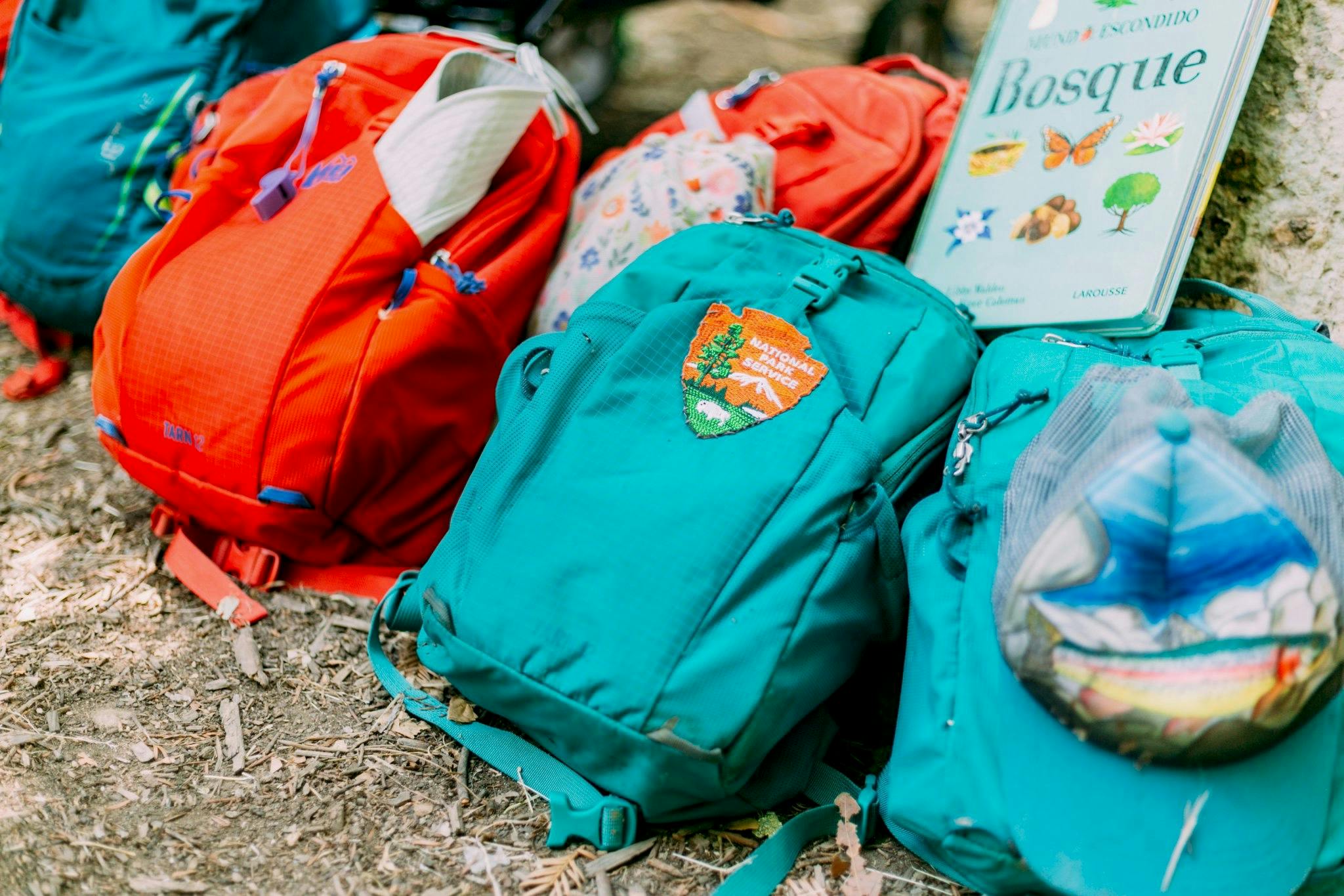 Several backpacks and a book on the ground