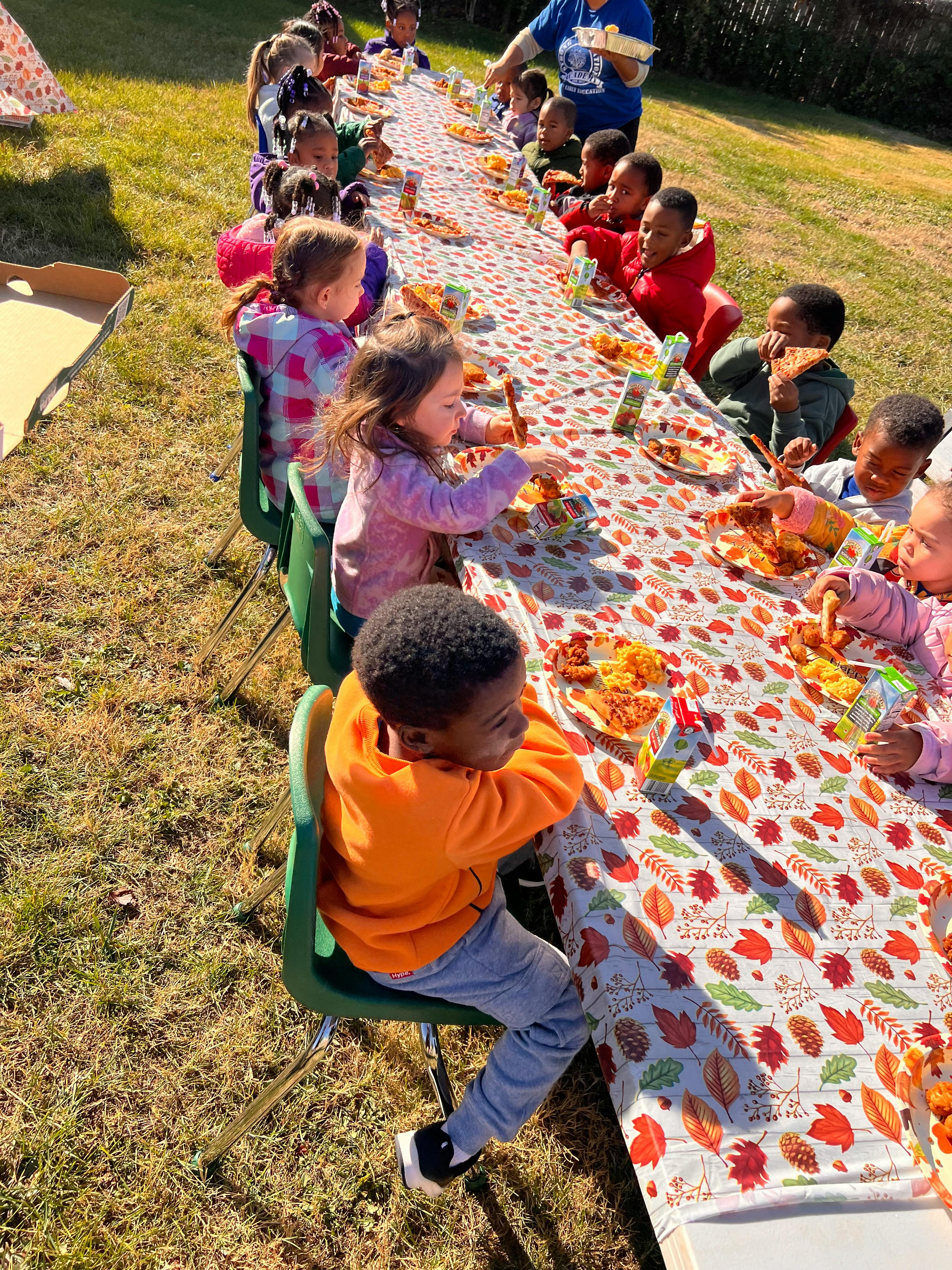 Children eating at a long table outdoors