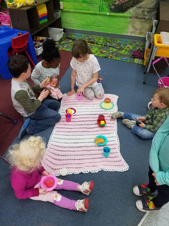 Children playing with dolls and toy food on a blanket