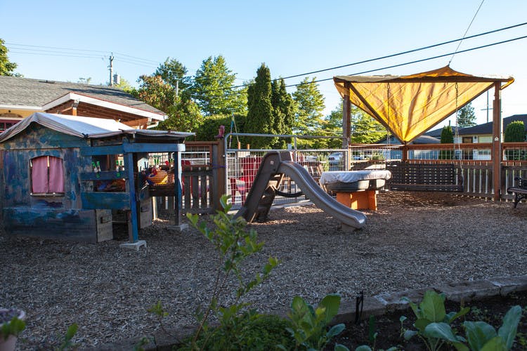 Playground with a slide, playhouse, and a yellow canopy