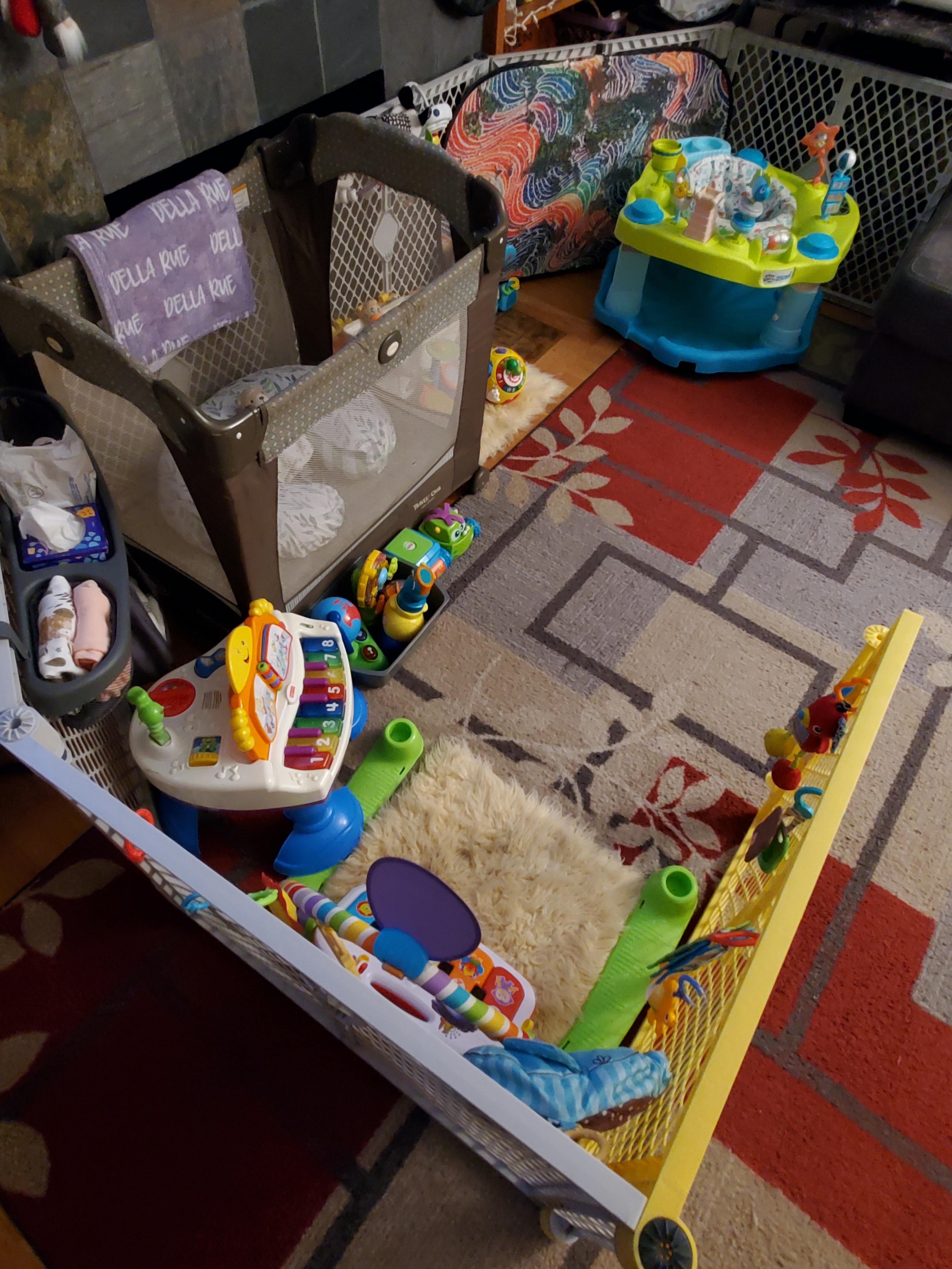 Playpen and various baby toys on a patterned rug