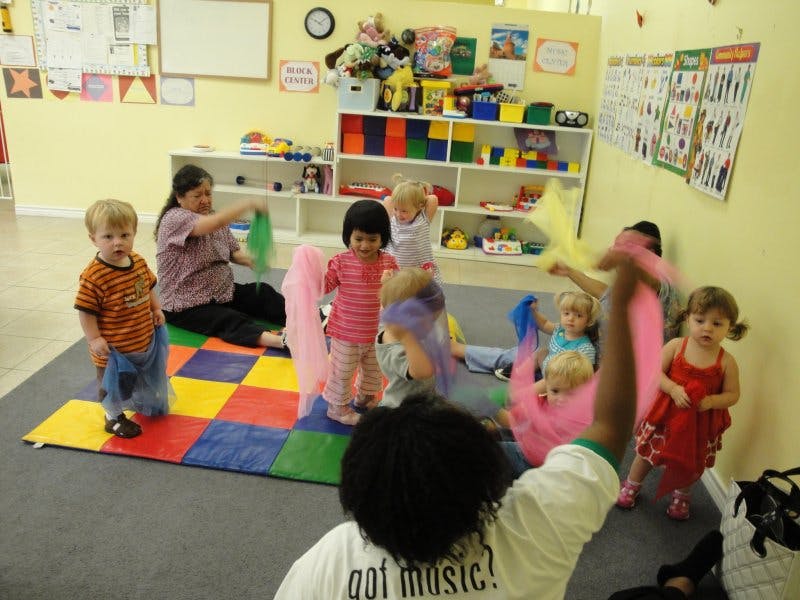 Adults and children playing with colorful scarves in a classroom