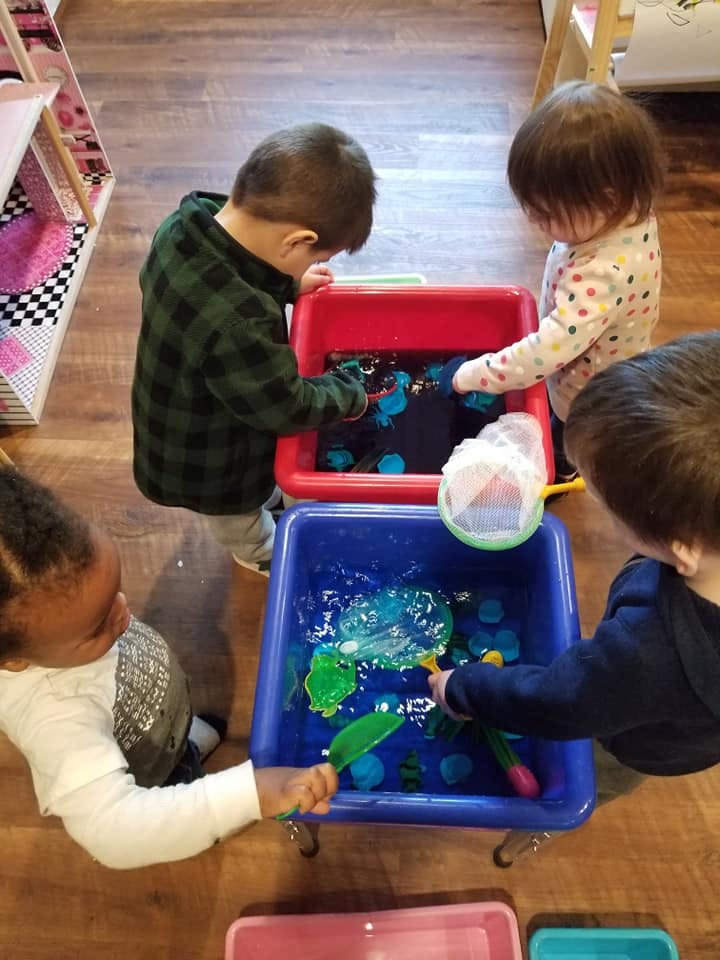 Children playing with water and toys in sensory bins
