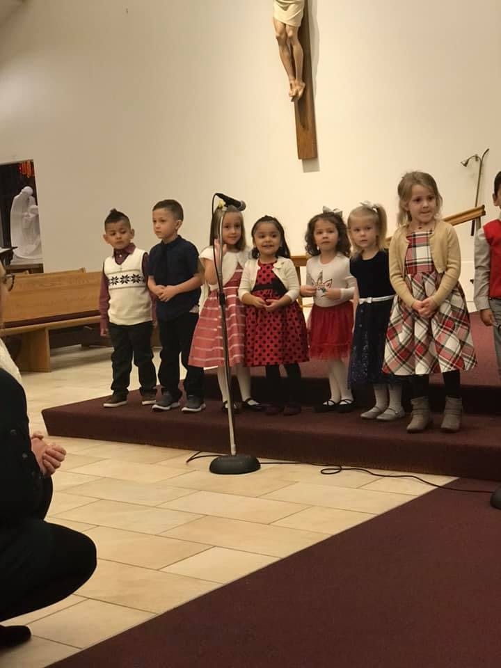 Group of children standing on a stage with a microphone
