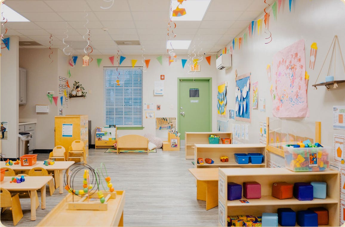 Colorful classroom with small tables, chairs, and play items