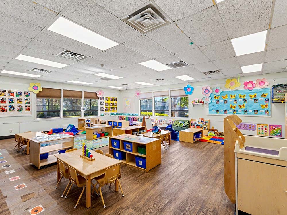 Empty classroom with small wooden tables and chairs, toys, and decorations