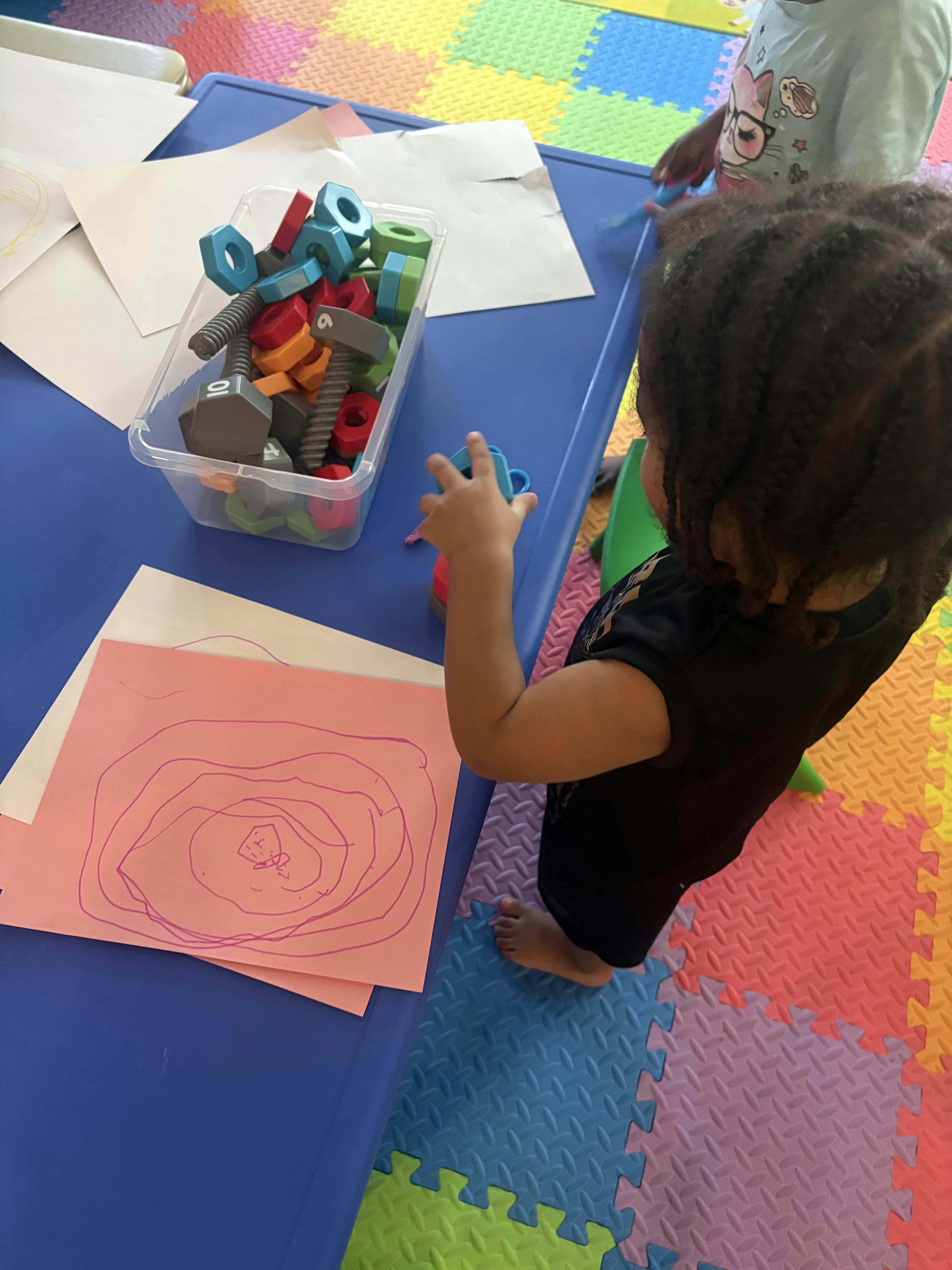Child playing with plastic nuts and bolts at a table