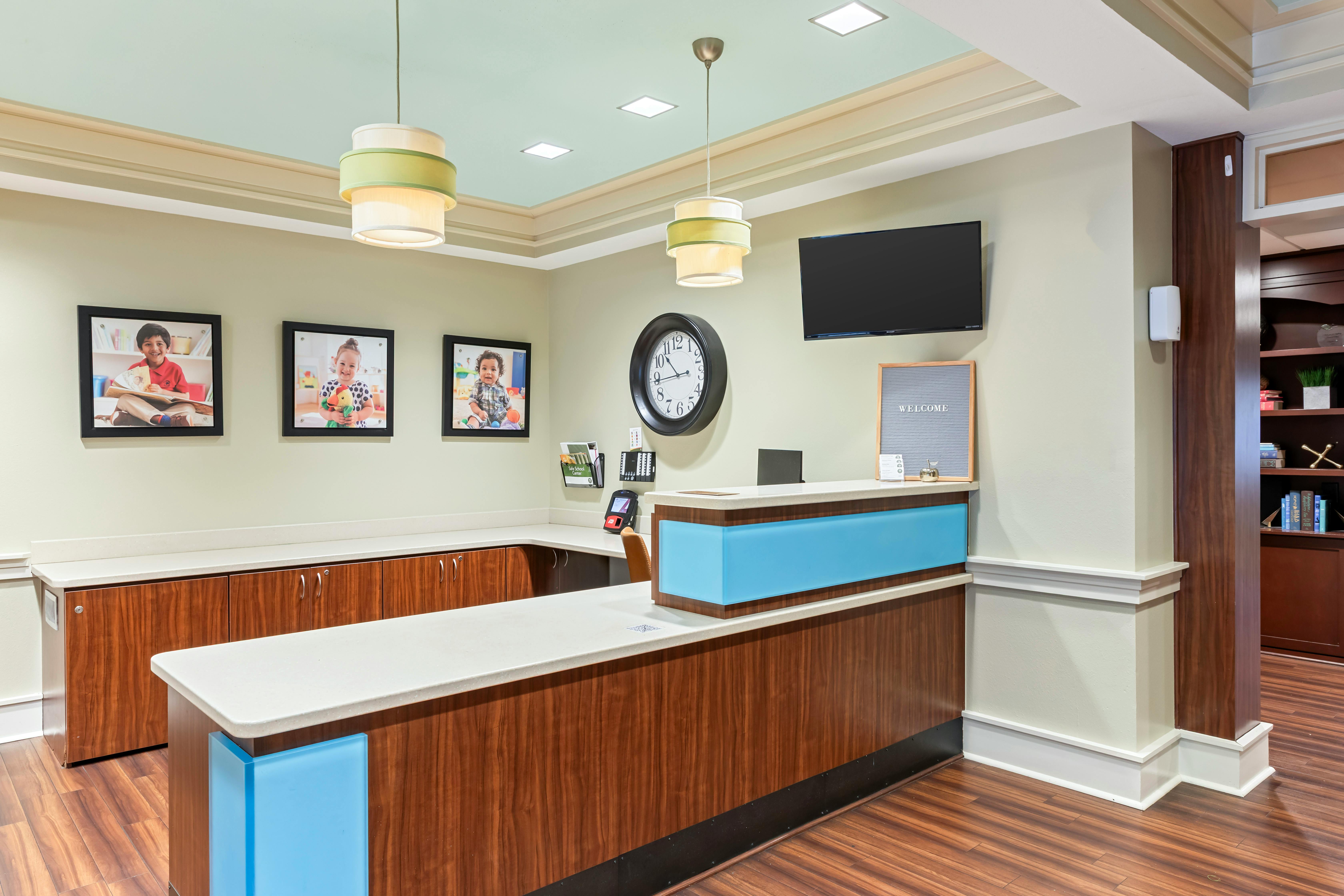 Reception desk with three framed images of smiling children on the wall