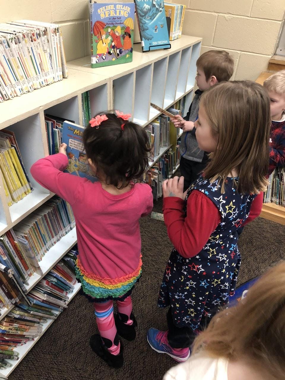 Children looking at books on shelves in a library