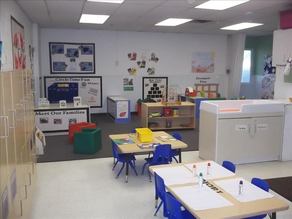 Classroom with small tables and chairs, activity centers, and storage units