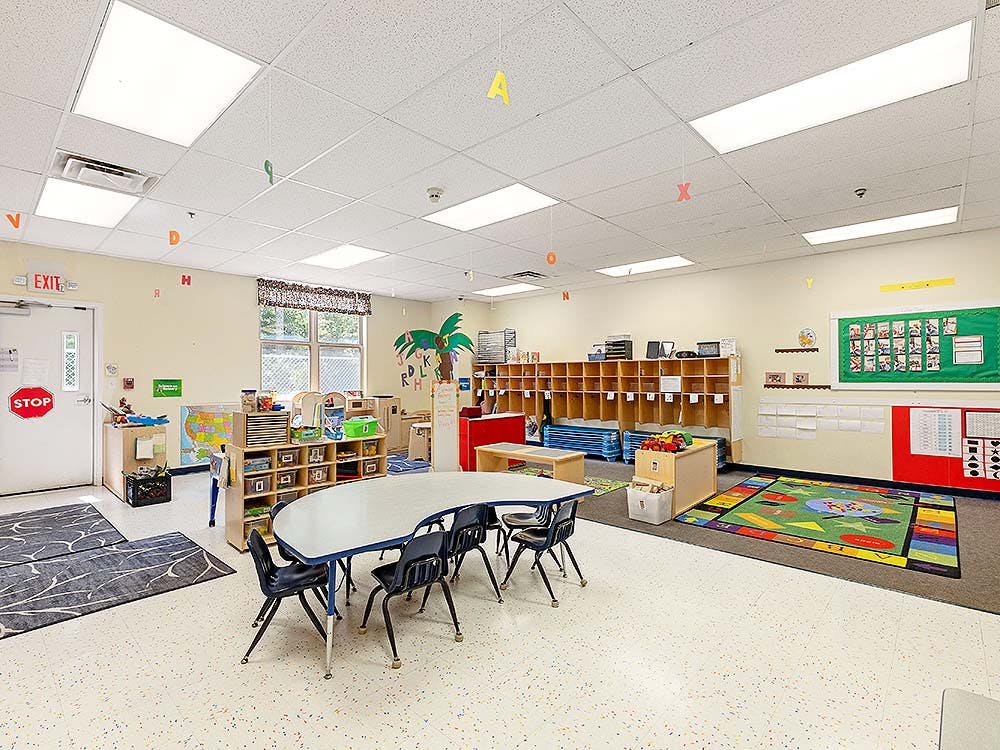 Classroom with child-sized tables and chairs, cubbies, and colorful decor