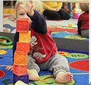 Child stacking blocks on a colorful rug