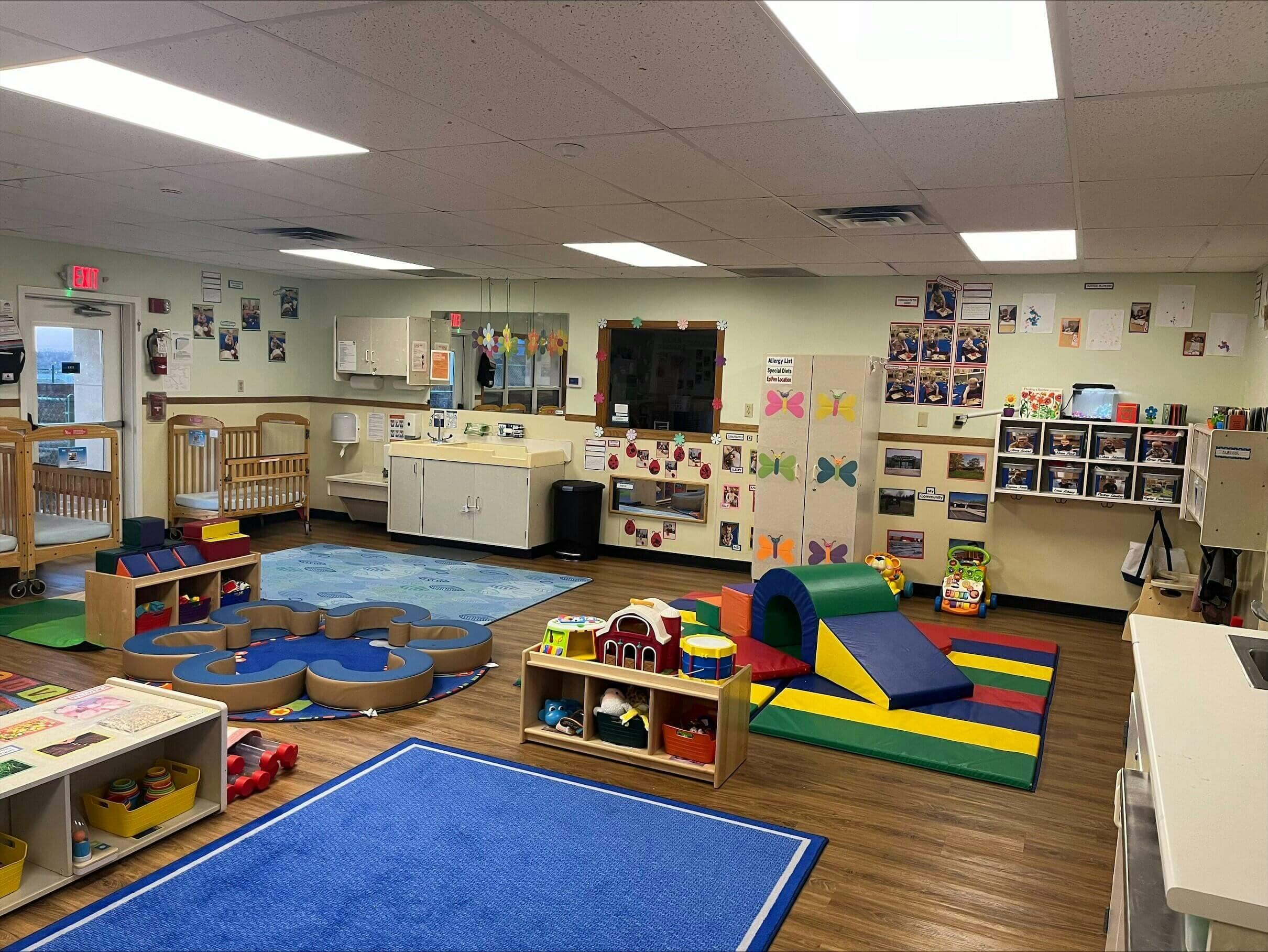 Classroom with cribs, play mats, and learning materials