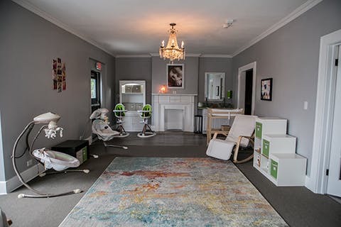 Room with baby swings, high chairs, and a rocking chair