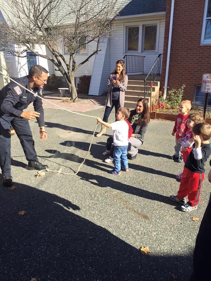 Adult and child holding a rope with other children and adults nearby