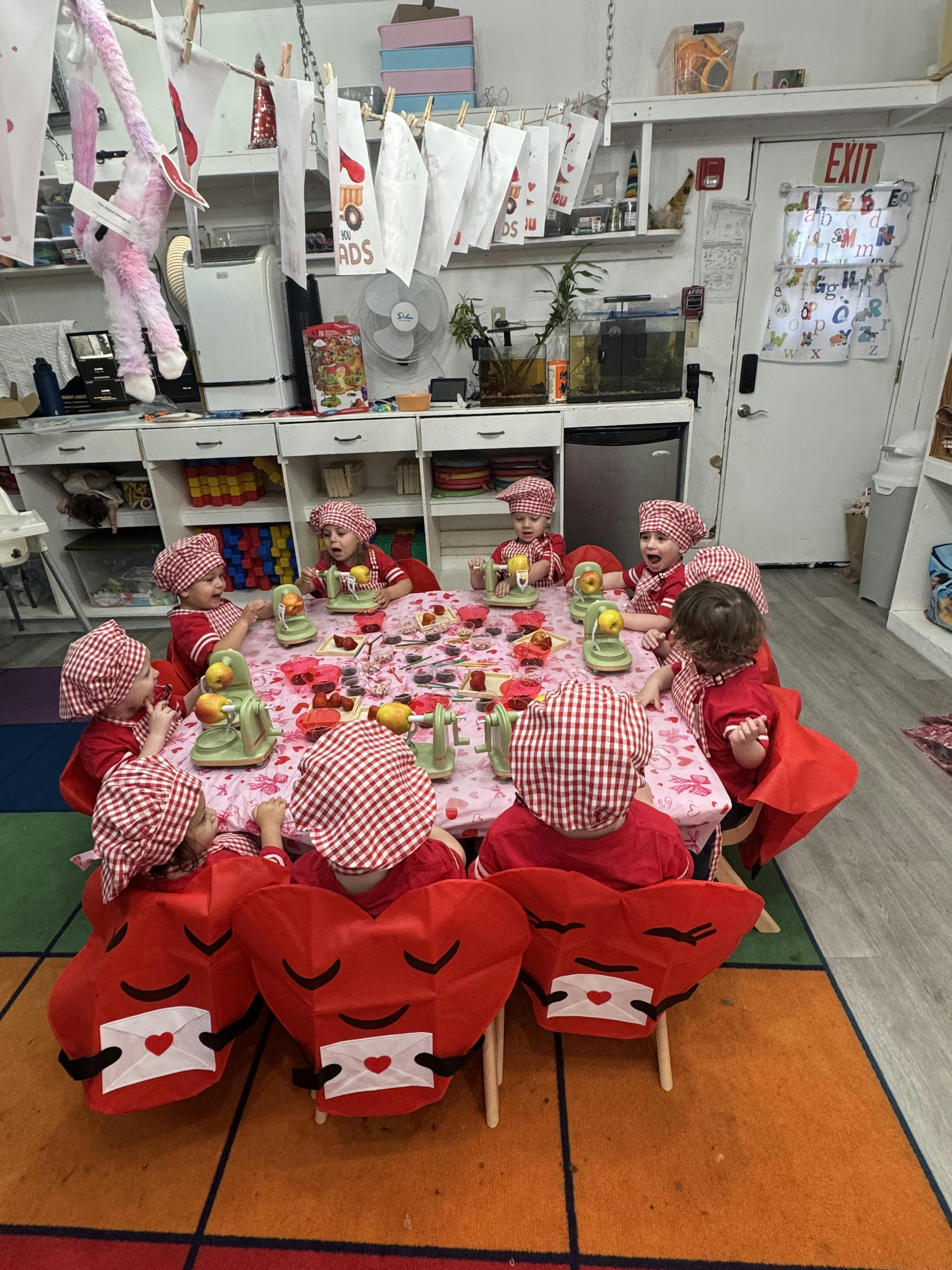 Children in red and white checkered hats at a table with apple peelers