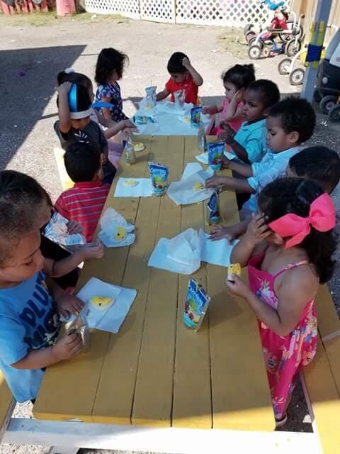 Children sitting at a picnic table with snacks and drinks