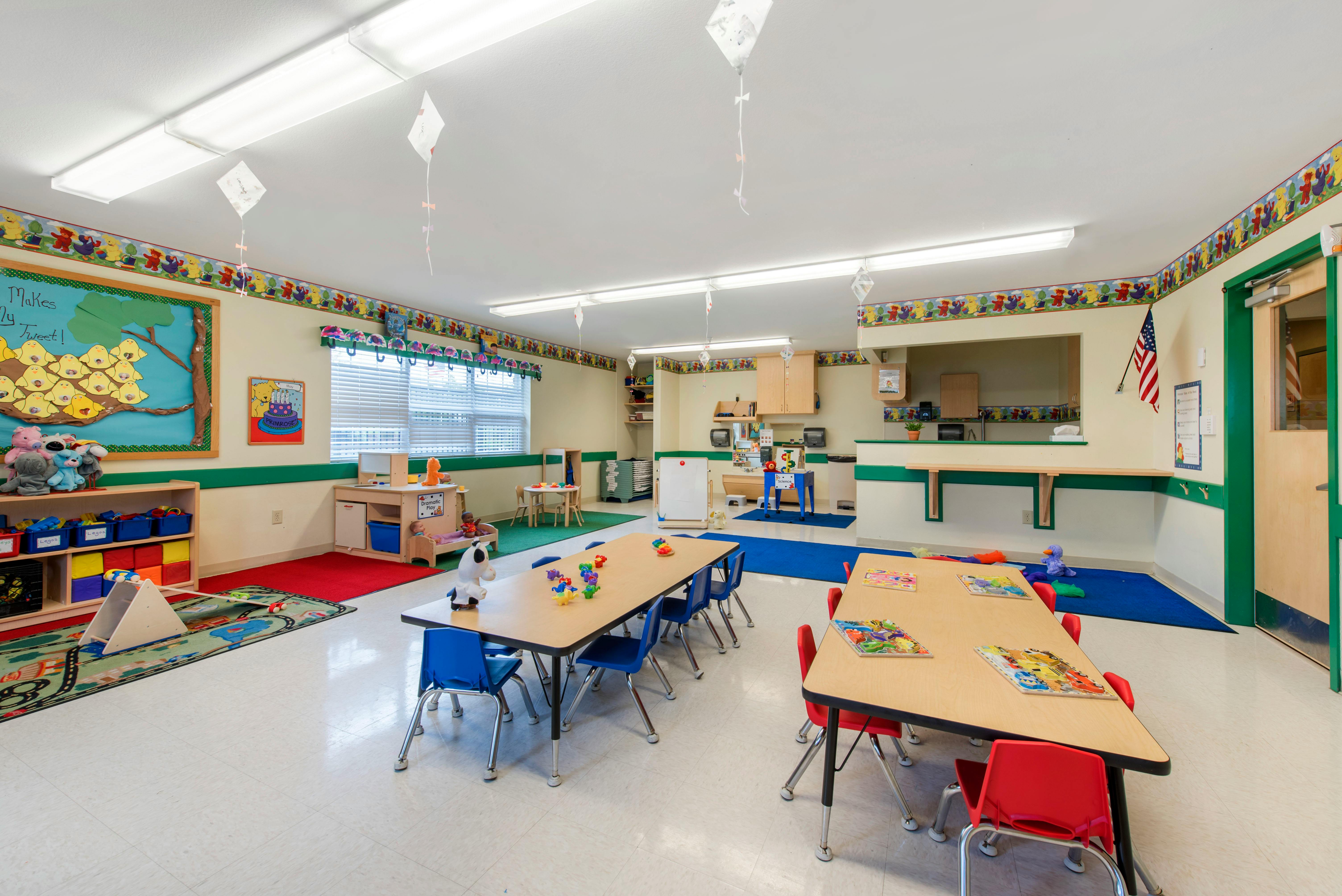 An empty and colorful classroom with small tables and chairs
