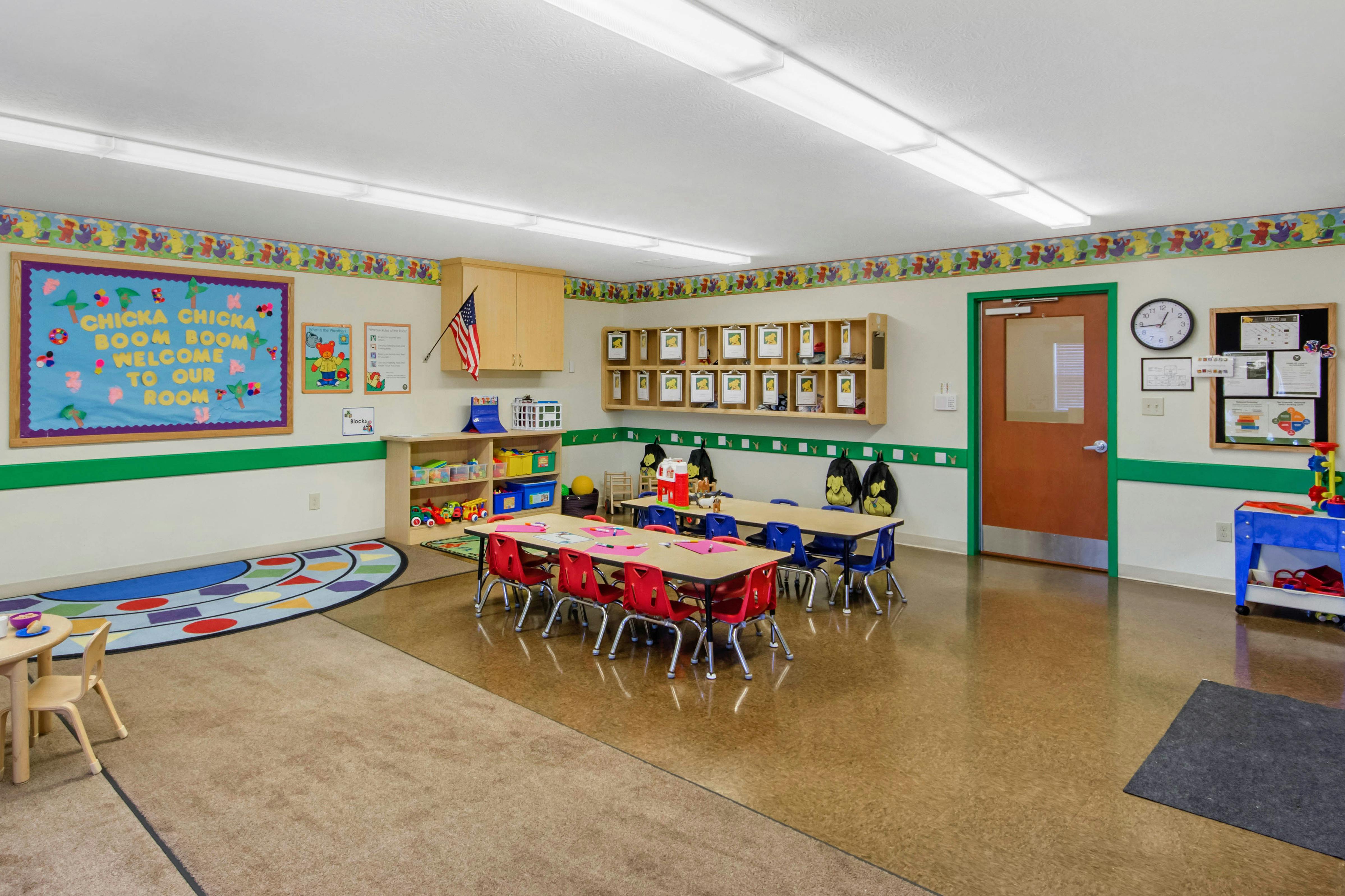 Colorful classroom with small tables and chairs, and a \"Chicka Chicka Boom Boom\" sign