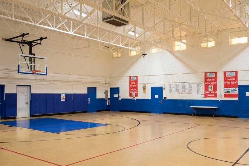 Empty indoor basketball court with a hoop and blue walls