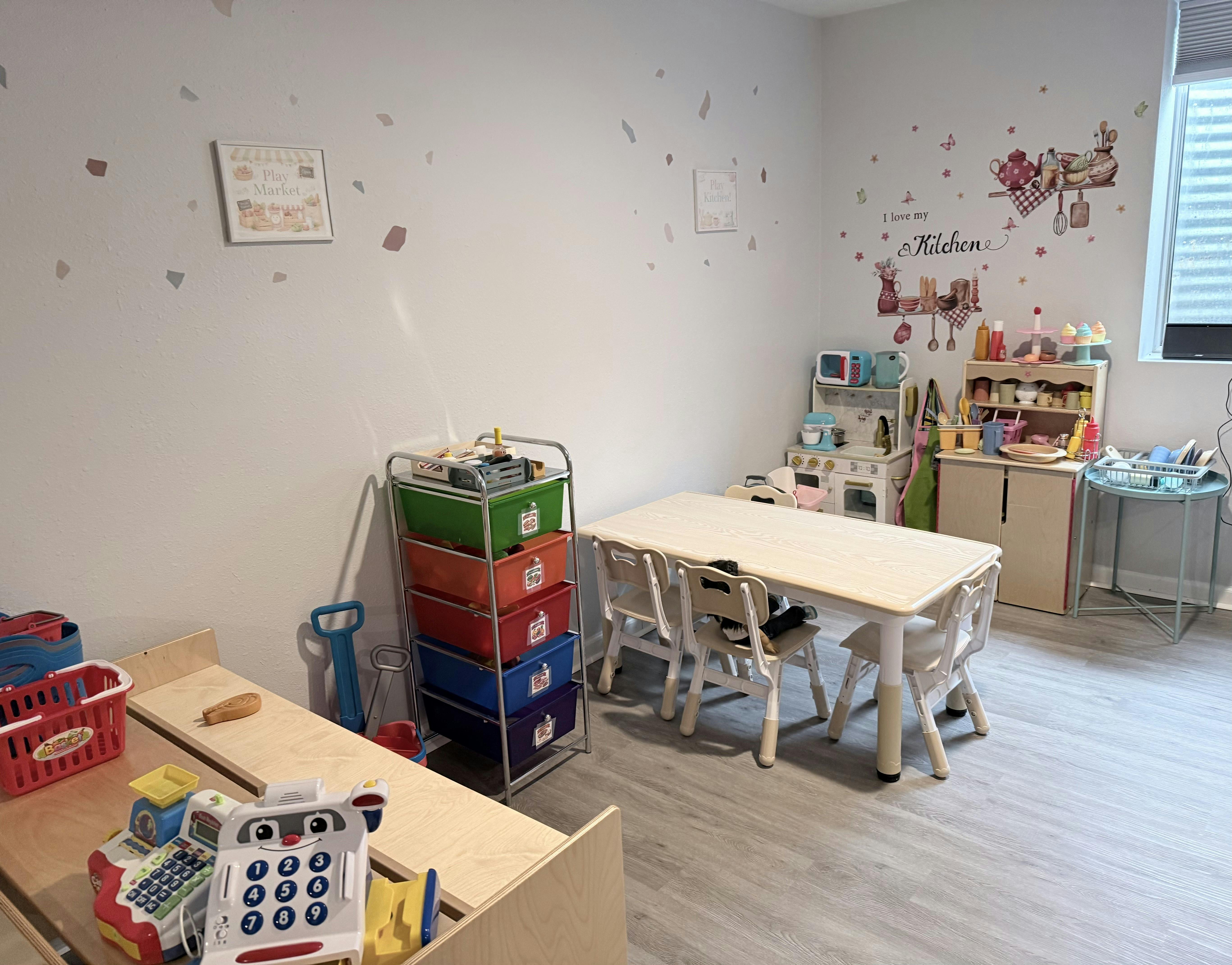 Playroom with children's table and chairs, toy kitchen, and toy market stand