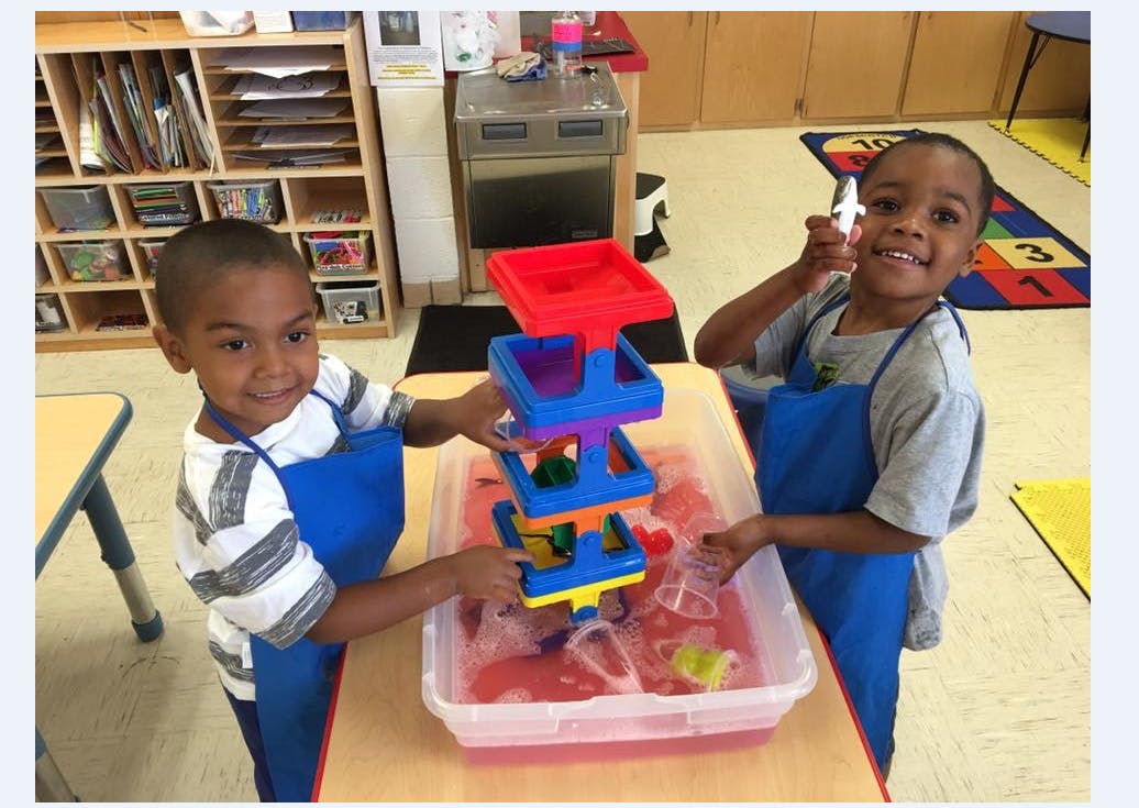 Two children playing with a water table toy in a classroom